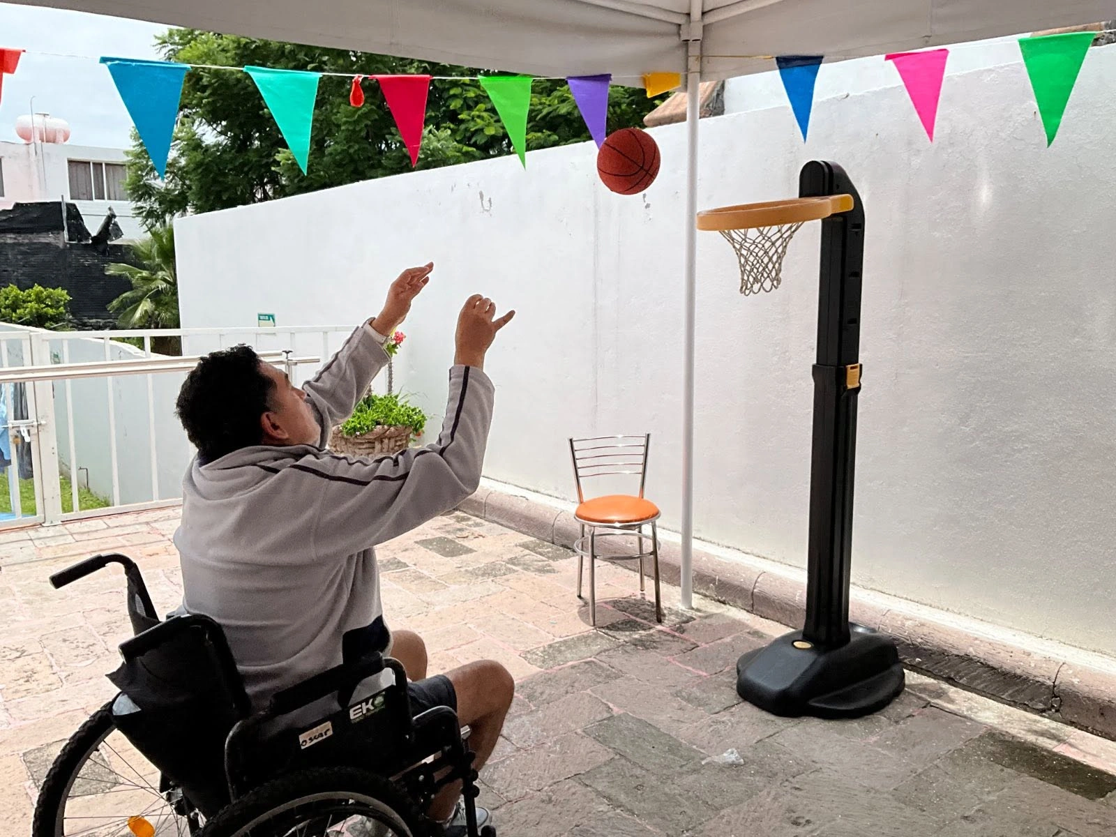 Residente participando en juego de básquet adaptado en el jardín del centro